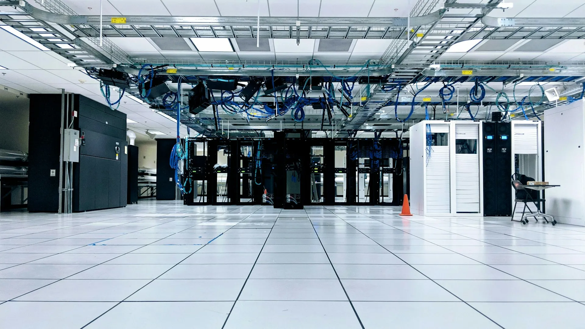 Rows of server cabinets under blue cabling in a data centre