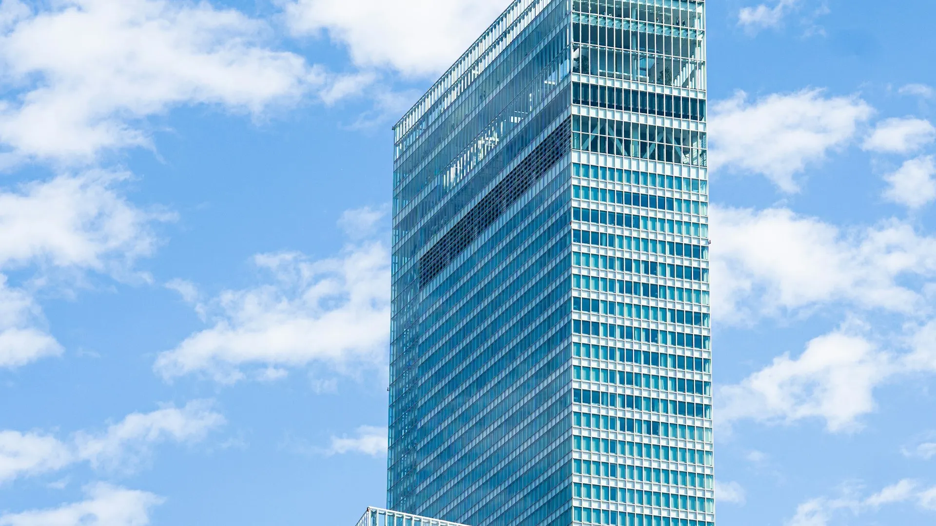 A blue glass office tower seen from below